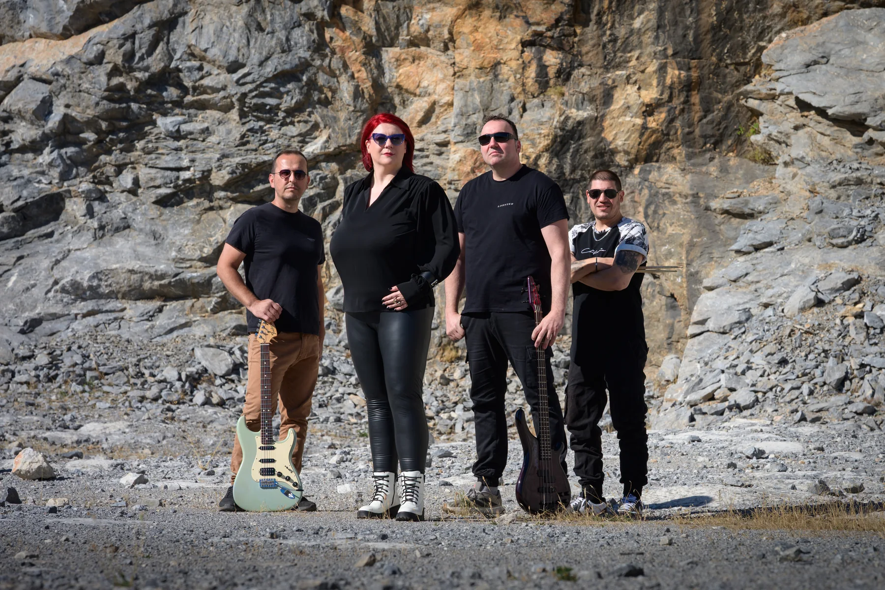 The four members of Rust n Groove with guitar, bass and drumsticks against the stone of Asvestochori quarry.